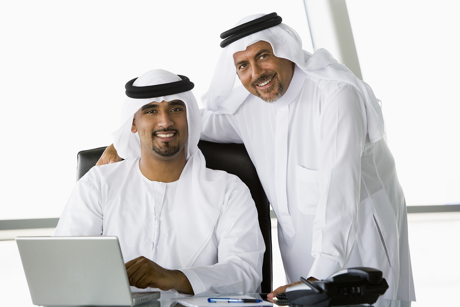 Two businessmen in office with laptop smiling (high key/selective focus)
